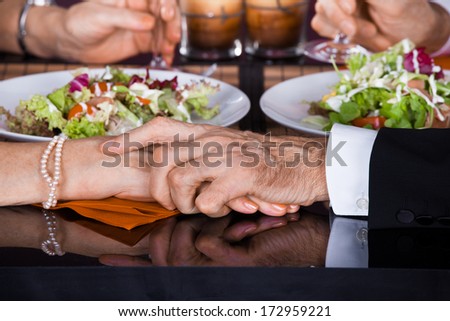 Hand Of An Mature Man Touching The Hand Of An Mature Woman At Dinner In Restaurant