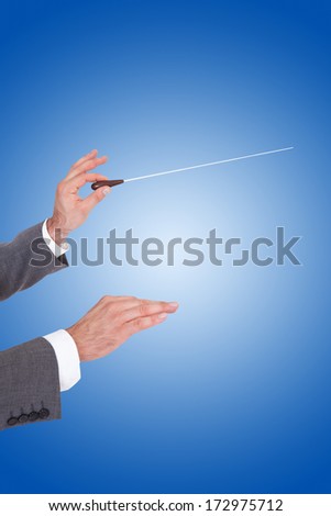 Close-up Of A Person Directing With A Conductor\'s Baton On Blue Background