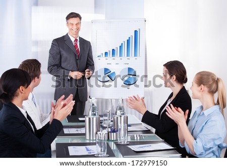 Group Of Happy Businesspeople Appreciating Businessman At Conference
