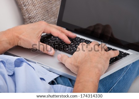 Close-up Of A Man Typing On Laptop Sitting On Couch