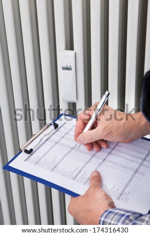 Portrait Of Male Plumber Taking Reading On Clipboard Of Machine