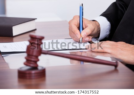 Male Judge Writing On Paper In Courtroom