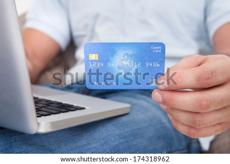 Close-up Of A Person\'s Hand Showing Credit Card While Using Laptop