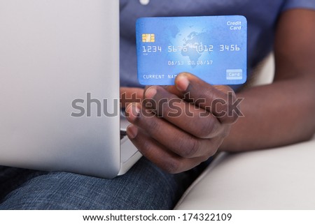 Close-up Of Hand Holding Laptop With Credit Card