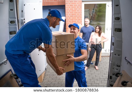 Happy Family Couple Watching Movers Unload Boxes From Truck Stockfoto © 