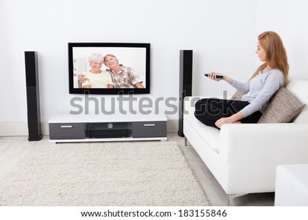 Portrait Of Young Woman Sitting On Couch Watching Movie