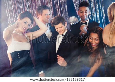 Smiling young friends dancing together at nightclub