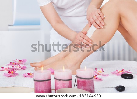 Beautician Waxing Woman\'s Leg Applying Wax Strip
