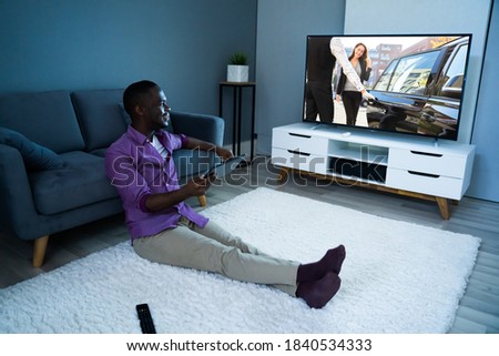 Large Version Of African Man Watching TV Movie Or Television Foto stock © 