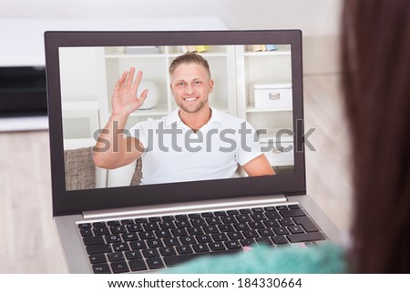 Young woman video conferencing with friend on laptop from home