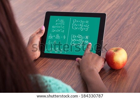 Cropped image of female student solving math problems on digital tablet at classroom desk