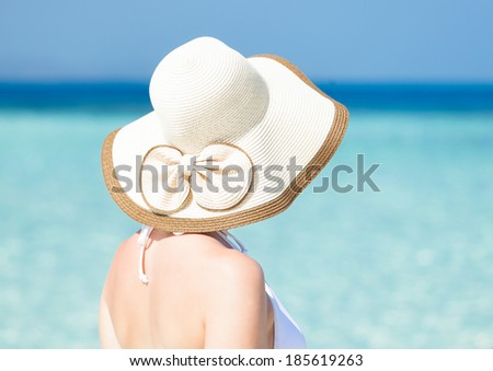 Rear view of young woman in bikini wearing sunhat at beach