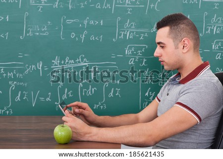 Side view of young male student using digital tablet in math\'s class