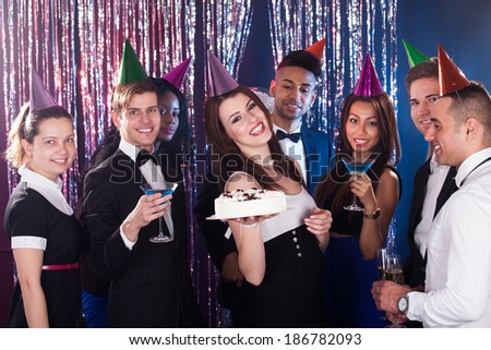 Portrait of happy multiethnic friends celebrating birthday at nightclub