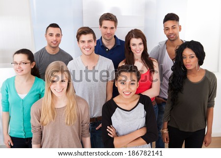 Group portrait of smiling multiethnic college students standing together in classroom