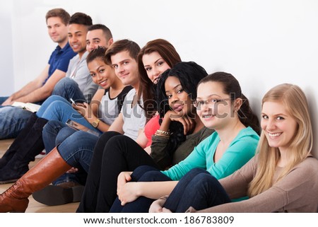 Portrait of confident university students sitting in a row on floor