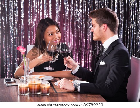 Loving couple looking at each other while toasting wineglasses at restaurant table