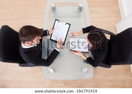 High angle view of business people discussing over documents at desk in office