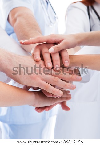 Doctors and nurses in a medical team stacking hands in a show of cooperation and solidarity isolated on white