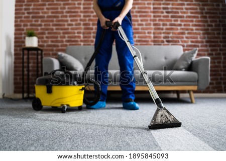 Janitor Cleaning Carpet With Vacuum Cleaner At Home