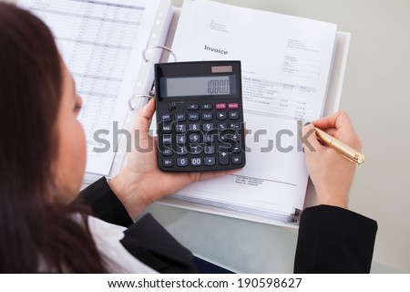 High angle view of female accountant calculating tax at desk in office