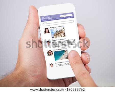 Closeup of man\'s hand holding smartphone with social site displayed on screen