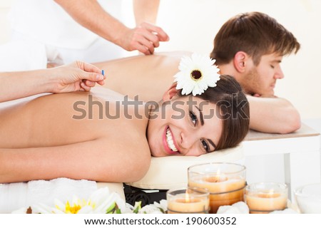 Portrait of happy woman undergoing acupuncture at beauty spa