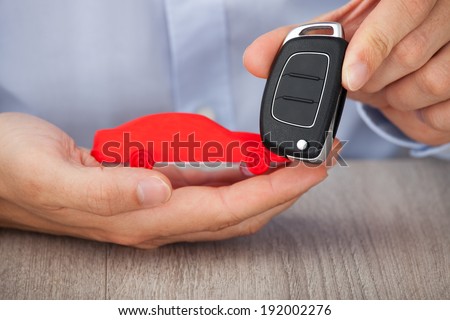 Midsection of businessman with keys and red car model at desk