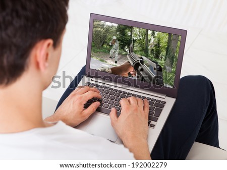 Midsection of young man playing action game on laptop at home