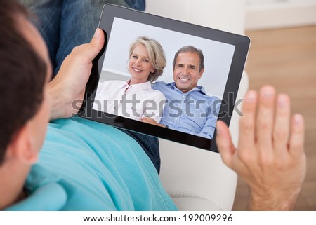 Cropped image of man having video chat with parents on digital tablet at home