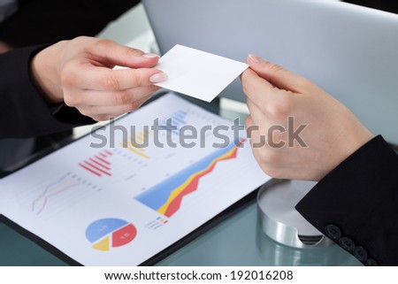Cropped image of businesswomen exchanging business card at desk in office