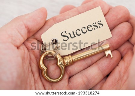 Closeup of man holding golden key with success tag