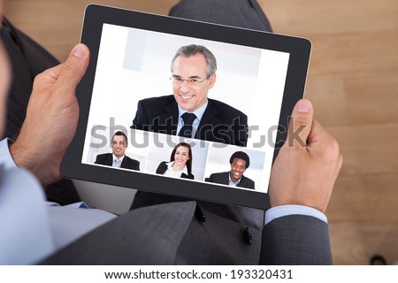 High angle view of businessman video conferencing with coworkers on digital tablet in office
