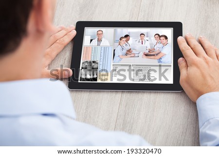 Cropped image of businessman video conferencing with medical team on digital tablet at desk in office