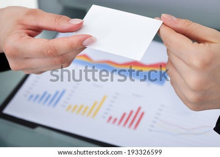 Cropped image of businesswomen exchanging business card at desk in office