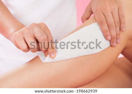 Closeup of female therapist waxing customer\'s leg at beauty spa
