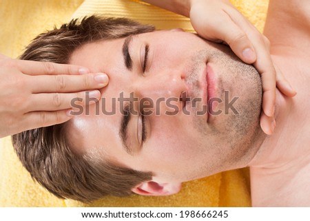 Directly above shot of relaxed young man receiving forehead massage in spa