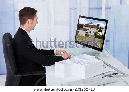 Side view of young male architect browsing property on computer in office