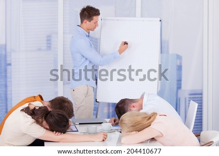 Colleagues getting bored during presentation given by businessman in office