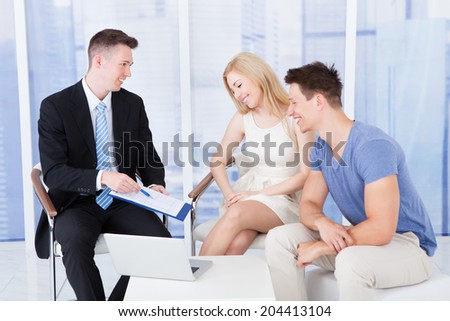 Financial consultant presenting new project investment to young couple in office