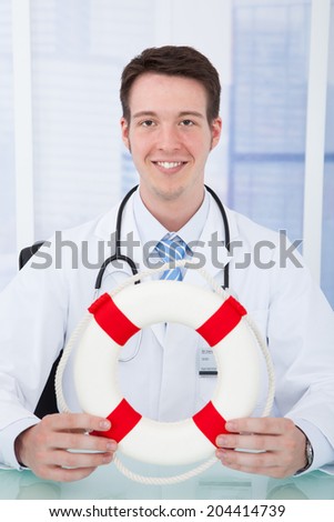 Portrait of confident young male doctor holding lifebuoy in clinic