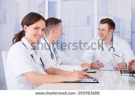 Portrait of happy young female doctor in board meeting
