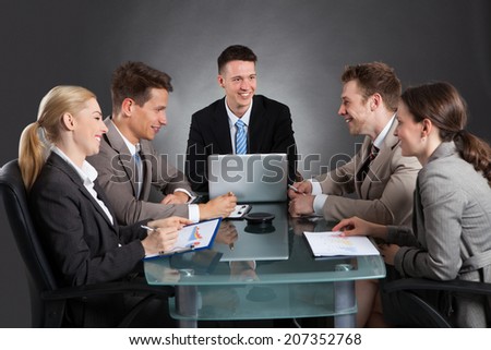 business people discussing in conference meeting at desk against black background