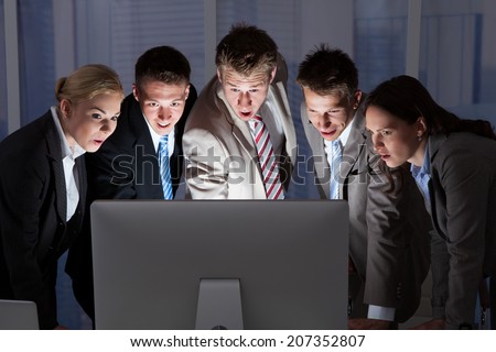 Surprised young business people looking at computer monitor in office