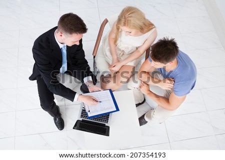 High angle view of financial consultant presenting new project investment to young couple in office