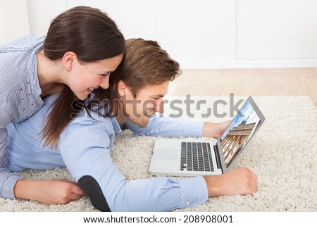 Side view of couple looking at Brandenburg Gate on laptop while lying on rug at home
