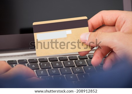 Cropped image of man using credit card and laptop to shop online