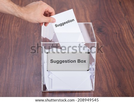 Cropped image of businessman placing suggestion slip into box on hardwood floor