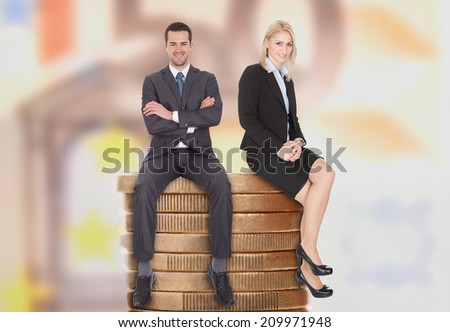 Full length of confident young business people sitting on stacked coins