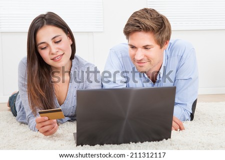Happy couple using laptop and credit card to shop online at home